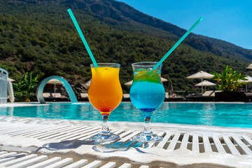 Two glasses with delicious bright tropical cocktail by the pool in the hotel