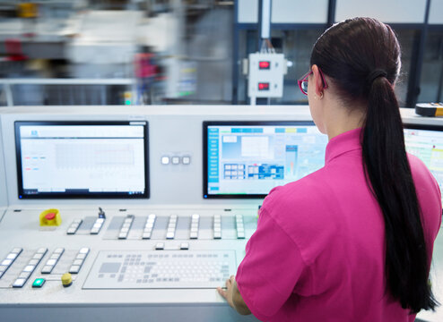 Young industrial employee operating CNC machine in factory