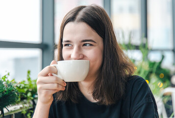 Portrait of a young woman with a cup of tea in a cafe.