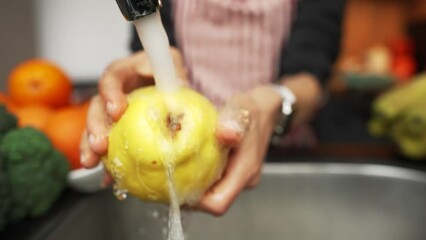 Female holding quince fruit in hands washing and cleaning it under water. Healthy nutrition. Slow motion shot - Powered by Adobe