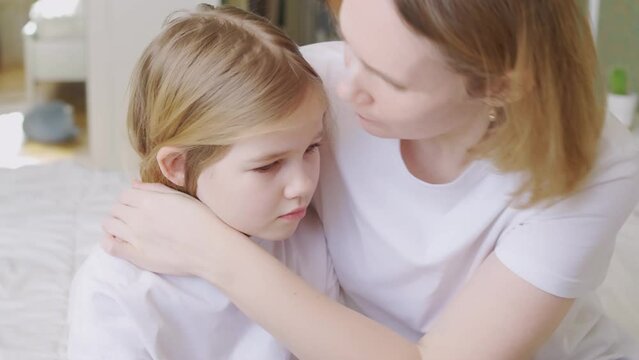 mom hugs and comforts her upset little daughter at home. 