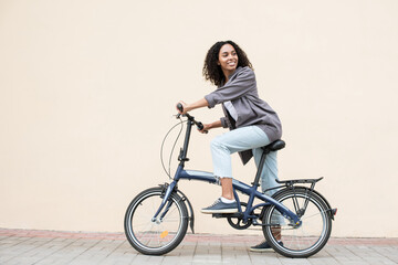Young beautiful woman on bike over white wall background in a city, Smiling student girl with...
