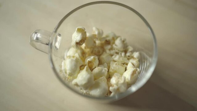 Picking popcorn from a glass cup with hand