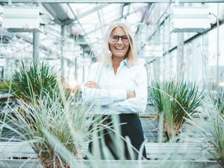 Cheerful scientist standing amidst plants at greenhouse