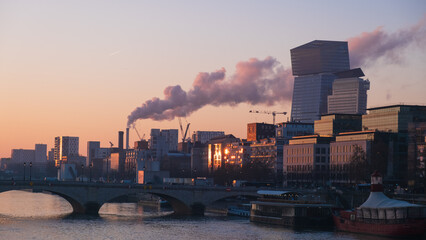 bridge of Tolbiac over the Seine river with chimney smoke of a plant behind at sunset