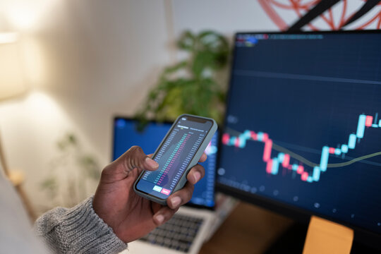 Trader Using Smart Phone For Trading Cryptocurrency At Home Office