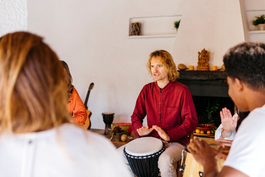Man playing bongo by friends in classroom