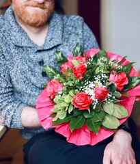 A man holding a bouquet of red roses, smiling