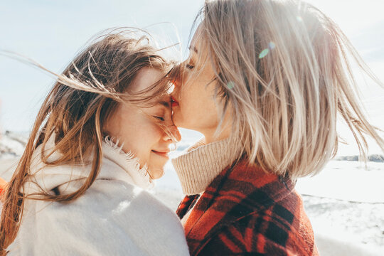 Mother kissing daughter on forehead at beach