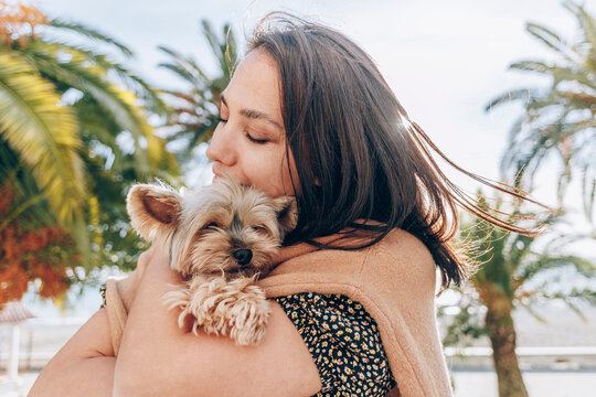 Woman hugging Yorkshire Terrier on sunny day