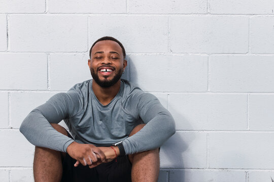 Smiling athlete sitting in front of white wall
