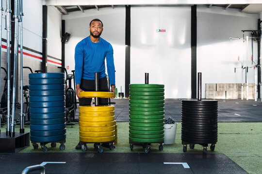 Young athlete standing near weight plates in gym