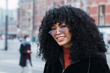 Smiling young woman with curly black hair wearing sunglasses