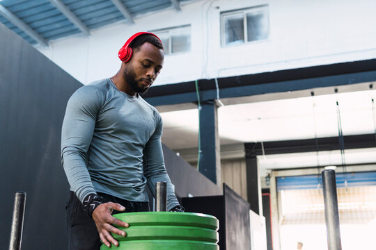Muscular athlete looking at stacked weights in gym