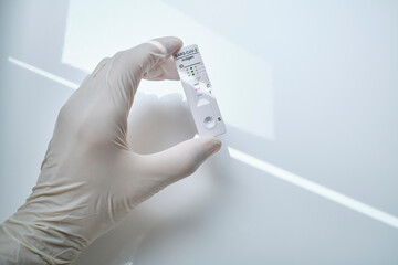 Hand holding rapid diagnostic device with COVID-19 positive results