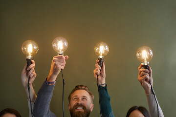 Close up of employees or workers hold lightbulbs develop creative business idea. Diverse...