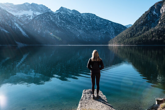Woman looking across Lake Plansee to Ammergau Alps, Reutte, Tyrol, Austria