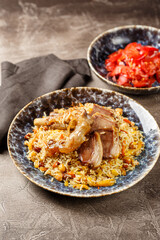 Pilaf with lamb meat in large dish and plate of tomato salad