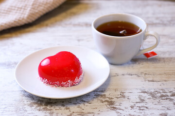 a heart-shaped cake and a cup of tea on a wooden table