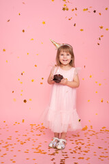 Obraz na płótnie Canvas Funny child girl in dress with birthday cupcake with candle on pink background