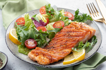 Grilled salmon fish fillet and fresh green lettuce vegetable tomato salad