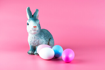 rabbit and painted multicolored easter eggs on pink background