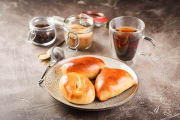 Sweet yeast dough pies with different fillings on platter and glass of tea