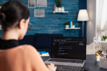 Student writing code on laptop in home office. Freelance programmer developing software. Freelancer...