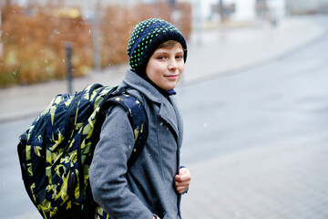 Portrait of preteen kid boy outdoors. Handsome child boy in coat and hat in winter. Schoolchild on...