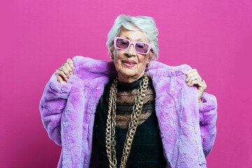 Beautiful and elegant old influencer woman. Cool grandmother posing in studio wearing fashionable...