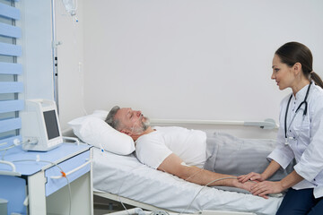 Obraz premium Attending physician monitoring mature man on intravenous therapy