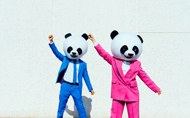 Storytelling image of a group of friends wearing giant panda head. Man and  a woman celebrating...