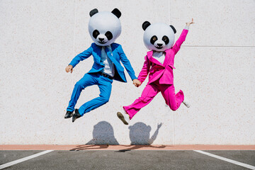 Storytelling image of a group of friends wearing giant panda head. Man and  a woman celebrating...