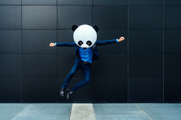 Storytelling image of a business man wearing a giant panda head. Funny cinematic concept about a...