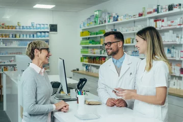 Papier Peint photo Pharmacie Two pharmacist giving prescription medications to senior female customer in a pharmacy