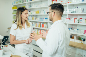 Fototapeta na wymiar Happy young male and female colleagues pharmacist working in a pharmacy