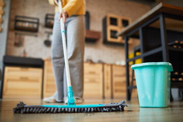 Close up background of unrecognizable woman mopping floors while cleaning cozy apartment, copy space