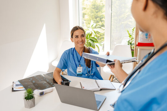 Multiracial Women Doctors Smiling And Talking While Working In Office