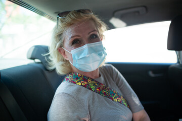 Elderly caucasian old granny aged woman take taxi car vehicle ride wearing face mask