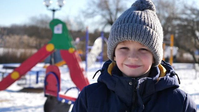 Happy baby boy having fun with snow in winter and smiling