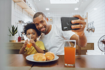 Happy African American Fther and little kid boy taking selfie with smartphone - Powered by Adobe