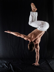 circus artist keeps balance on one hand isolated on a black background. concept of handstand and calisthenic