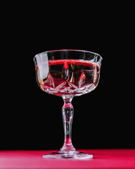 Glass of whiskey or other alcohol liquor served in a glass over red background Vintage glass of hard liquor.