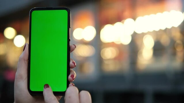 Point of View of voman at street Using Phone With Green Mock-up Screen Chroma Key Surfing Internet Watching Content Videos Blogs Tapping on Center Screen