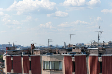 Fototapeta premium TV antennas on the roof of the house on the background of a blue sky with clouds