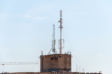 Cellular communication antennas on the roof of the house, against the blue sky. The Internet