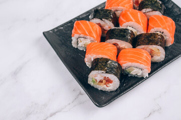 Sushi bar lunch menu, different sushi rolls with salmon, avocado and smocked eel on white marble table background. Online order delivery food online, takeout food concept