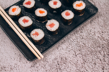 Classic sashimi with salmon or tuna fish, soy sauce and chopsticks on concrete table background - maki sushi roll, nori maki. Asian food delivery, online order food concept, sushi bar menu