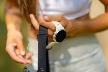 Close-up of woman using fitness smart watch device and chest strap heart rate monitor under workout