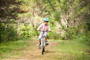happy child girl riding a bike on natural background, forest or park. healthy lifestyle, family day...